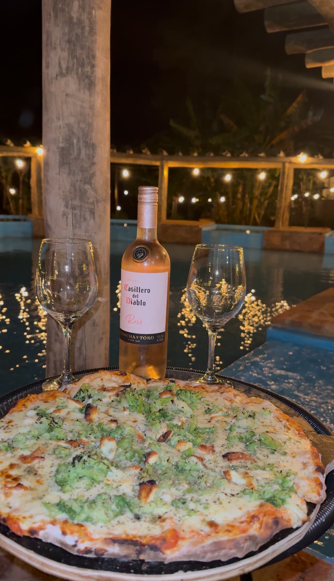 Pizza e vinho na piscina à noite